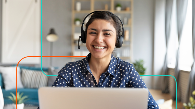 Woman of colour smiling with her headset on while she works as a data entry assistant on her laptop.