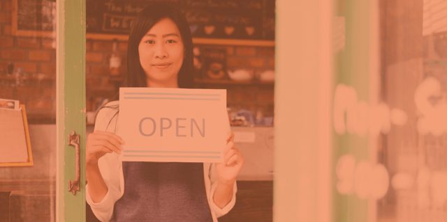 Holding an open sign in a small business storefront, Support Small Business Week: Why it