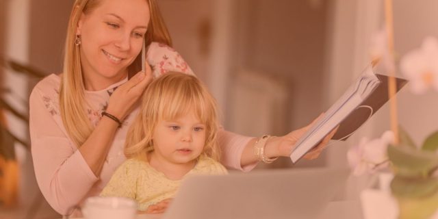 Work-life-balance with a Caucasian woman on a smart phone with a little child in her lap and holding a notebook in front of her laptop computer.