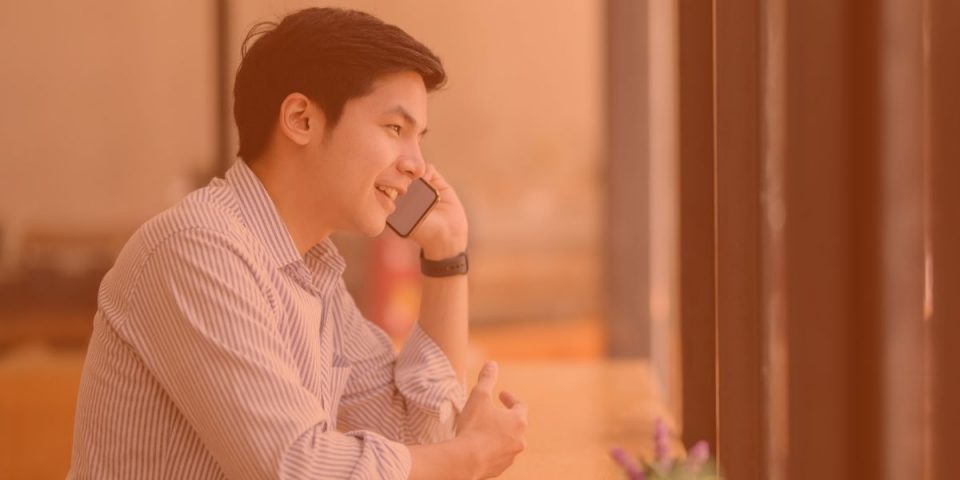 A younger East Asian man speaking on a cellphone while wearing a button up dress shirt learning how to build a powerful B2B sales prospect list with Virtual Gurus.