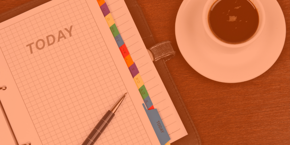 A dayplanner with a pen and a cup of coffee on a wood desk showing how to forge a productive routine with Virtual Gurus.