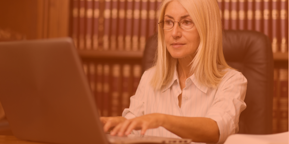 A female lawyer with blond hair and glasses is having a video call with a Virtual Gurus virtual legal assistant.
