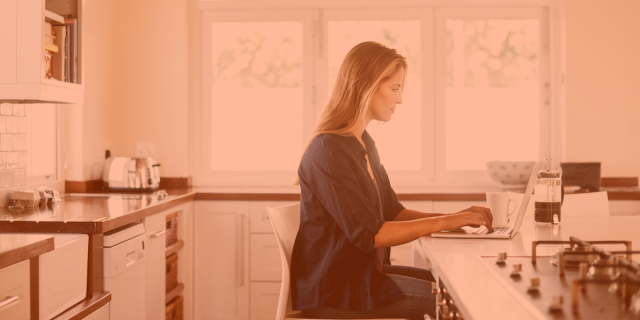 Image of woman sitting in kitchen working on laptop