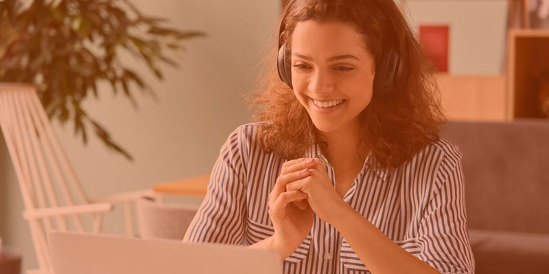photo of woman with headphones smiling at computer