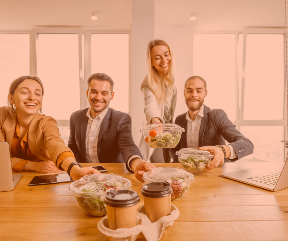 employees gathered at lunch table reaching for salad
