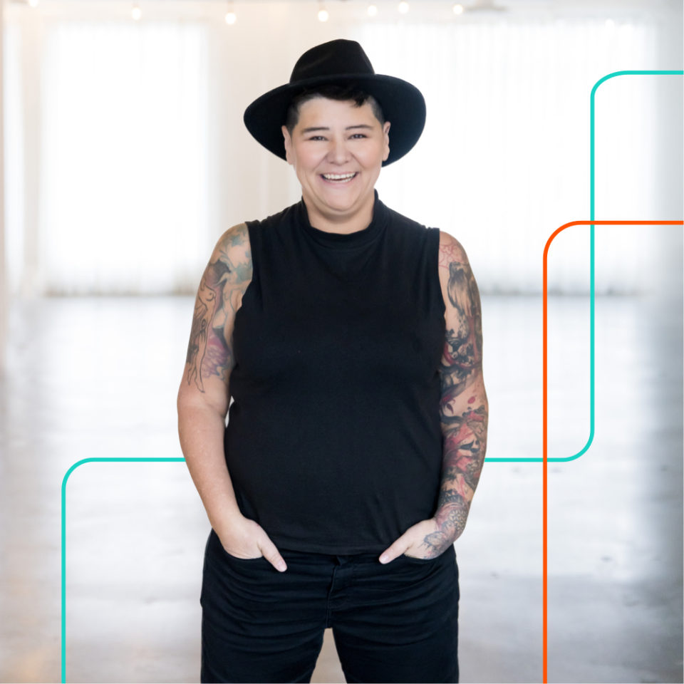 Bobbie Racette, CEO and Founder of Virtual Gurus walking down an alley wearing a black hat and tattoos on her arms.
