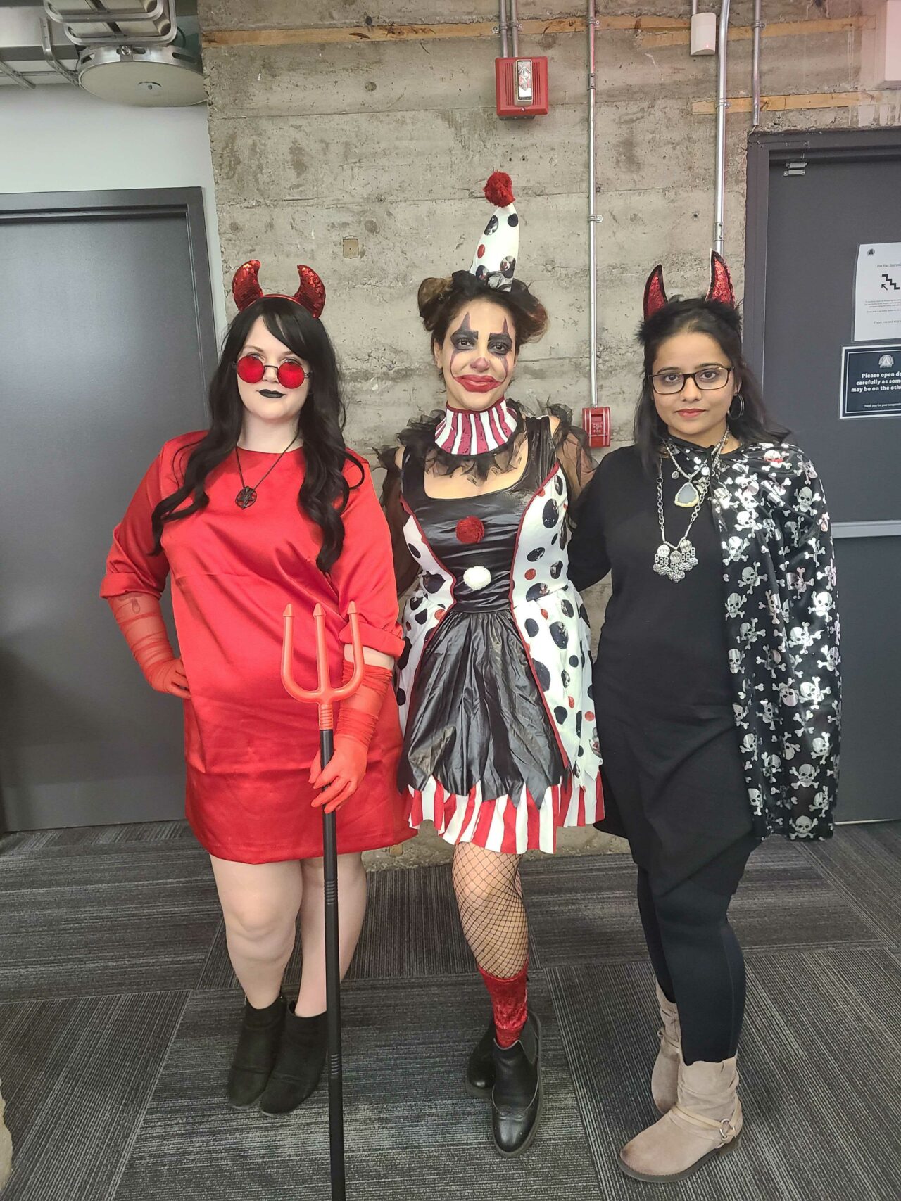 Three women Virtual Gurus staff members dressed up for Halloween one as a clown and two as devils.