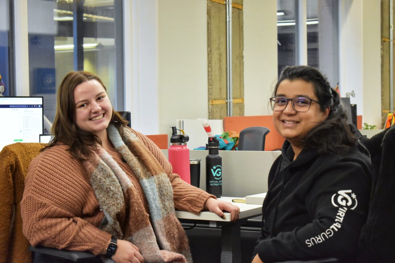 Deux jeunes membres diversifiés du personnel des gourous virtuels, assis dans le bureau, le sourire aux lèvres.