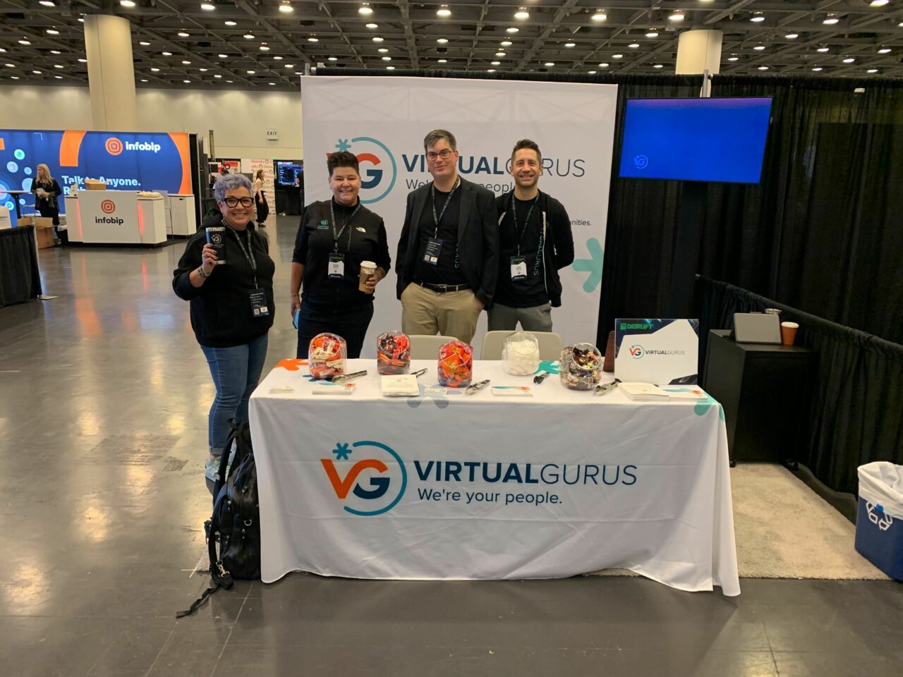 Bobbie Racette, with three Virtual Gurus staff members standing behind a Virtual Gurus booth at a tradeshow.