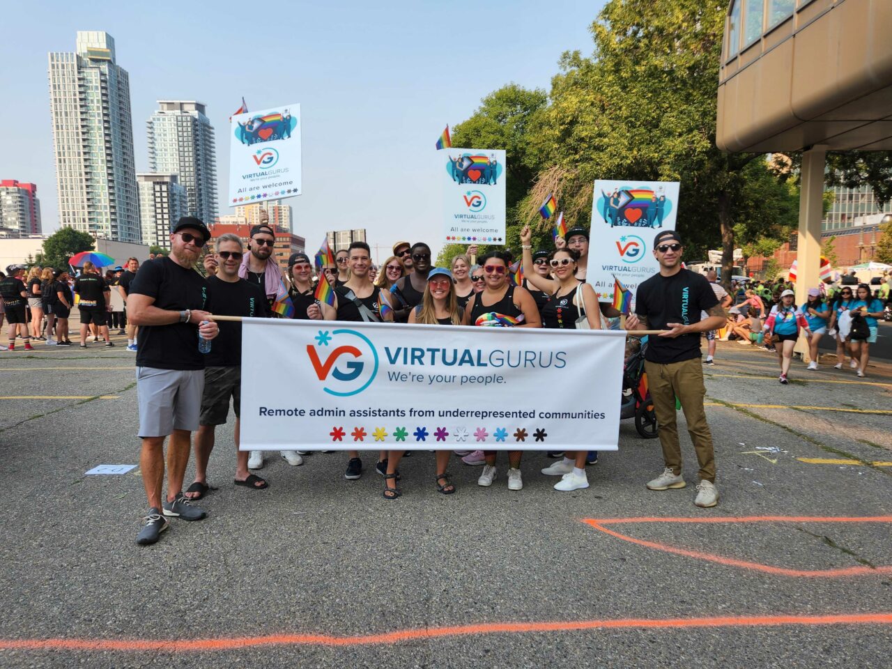 The Virtual Gurus team is standing on the street holding a company banner celebrating Pride Parade in Calgary.