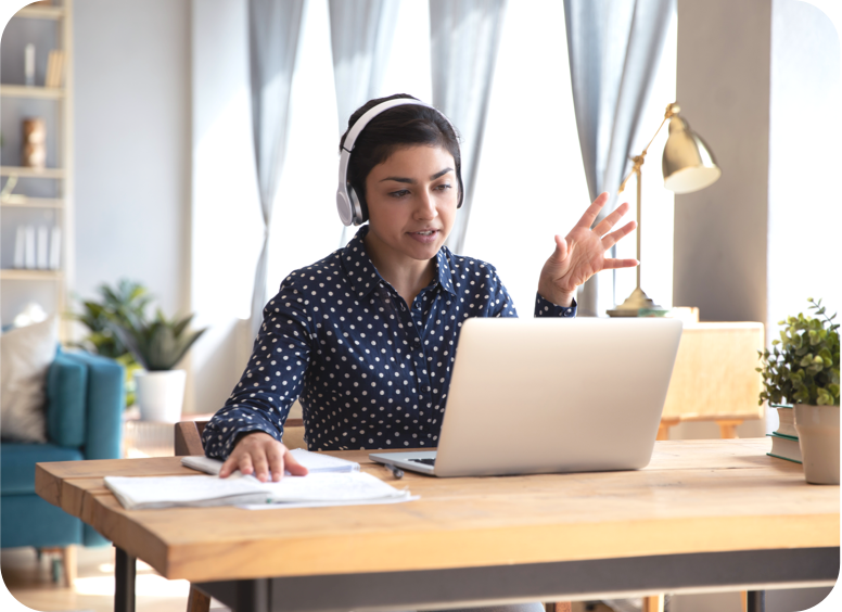 A young female virtual assistant working in her home office wearing headphones on her laptop.