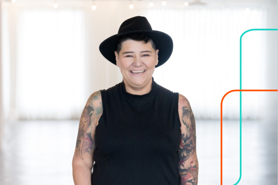 Bobbie Racette, fondatrice et PDG de Virtual Gurus et askBetty, souriante, portant un chapeau noir et des tatouages sur les bras.
