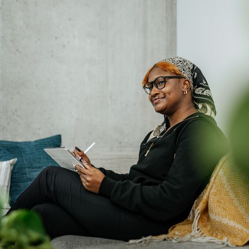 Young African American woman happily sitting in her comfortable home office while working as a virtual assistant.