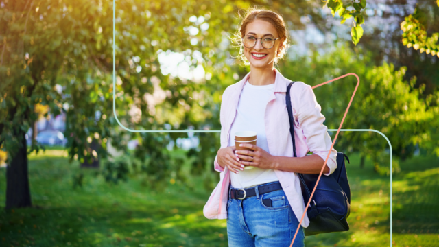 Woman taking care of her workplace mental health by taking a break from work and walking in the park and sipping coffee.
