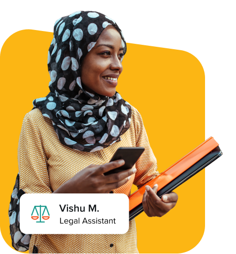 Woman of colour with polka dot head covering holding her phone and appears while smiling as she works as a virtual assistant.
